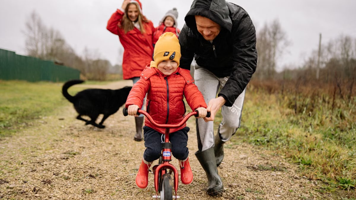 A joyful scene of a father helping his child ride a bike outdoors.